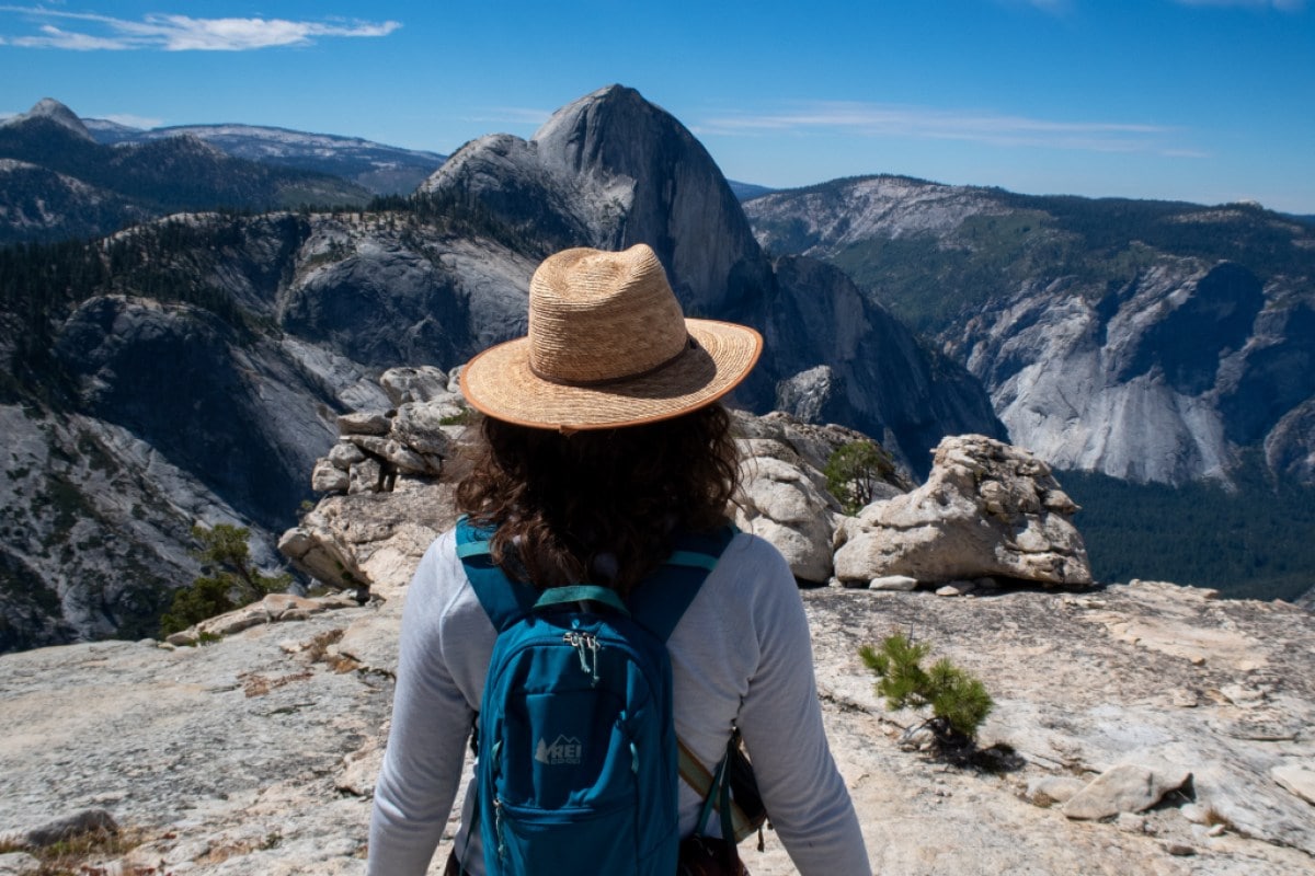A woman wearing a hat looks at a view of Yosemite National Park