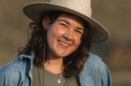 A photo of a woman smiling, wearing a white hat