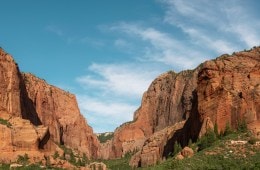 A photo of red rock formations against a blue sky with some wispy clouds