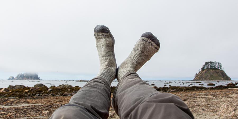 A person with socked feet in the air with coastal background