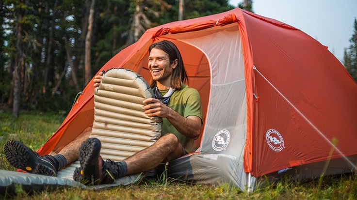 A backpacker inflates his pad while sitting in the door of the Big Agnes Copper Spur HV UL2 tent in Colorado.