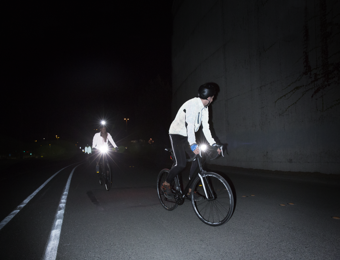 Two people riding bikes in the dark with bike lights on.