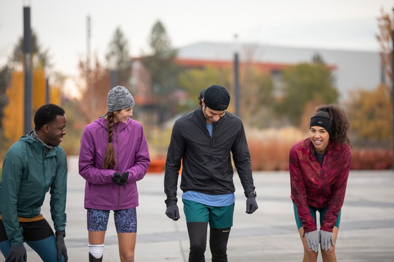 Four people stand side by side getting ready to go on a run.