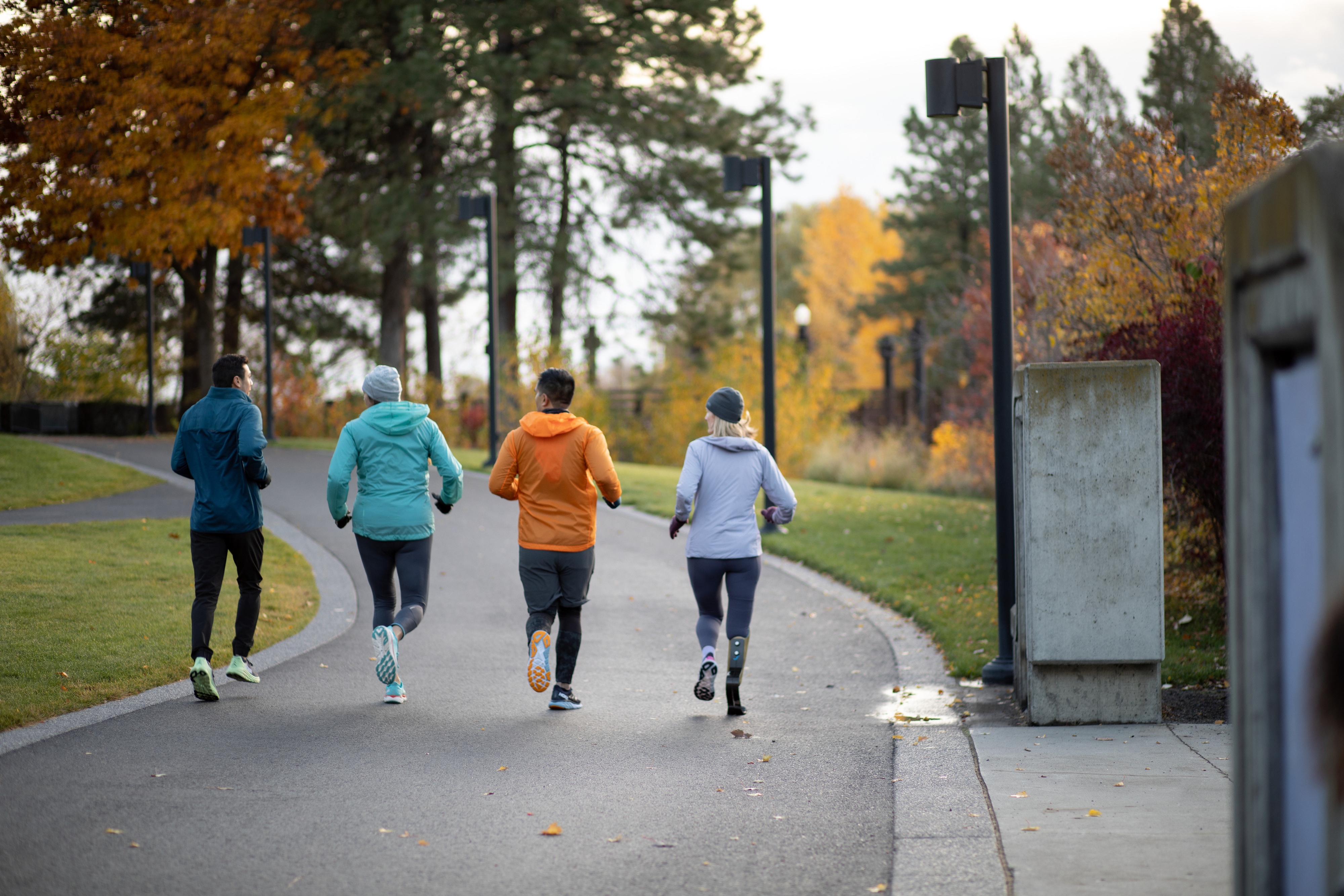A group of four people are on a run through a local park