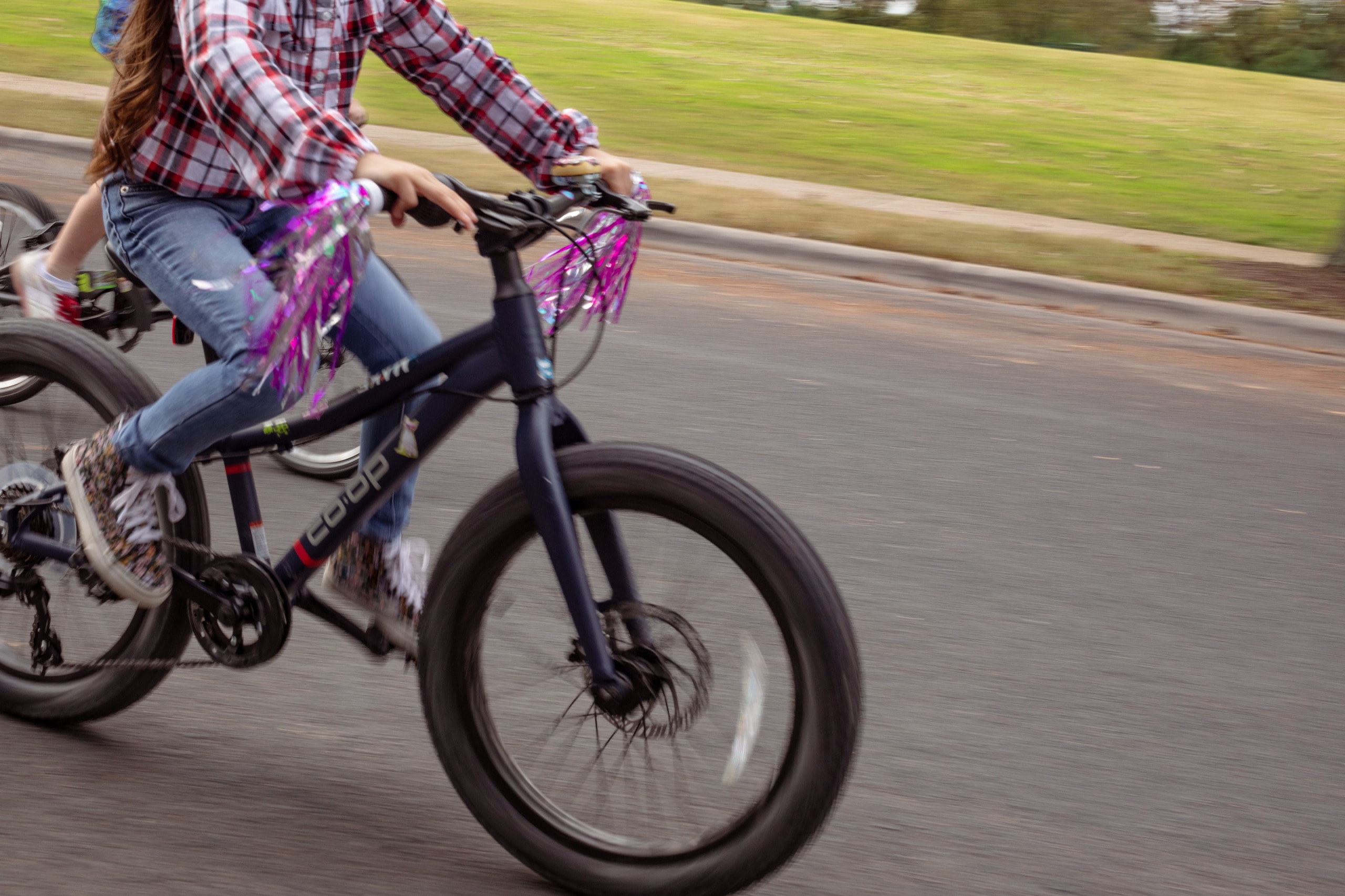 A child rides a bike with pink tassles