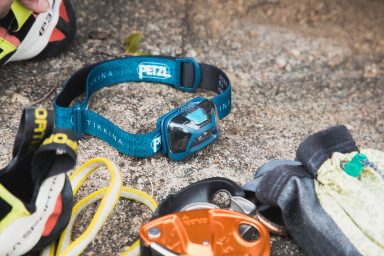 A headlamp lays on a rock next to other pieces of gear