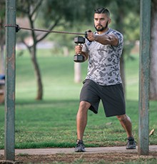Goal_BCS_Push_Pull_B Finishing a dumbell and resistance band push and pull exercise in a park