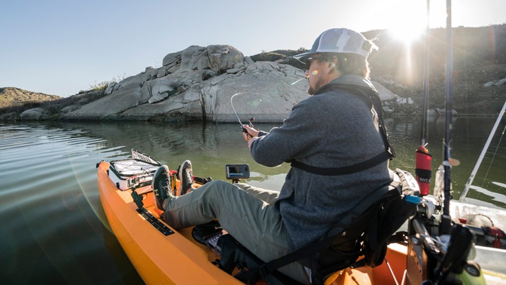 A person fishing from their kayak at sunset