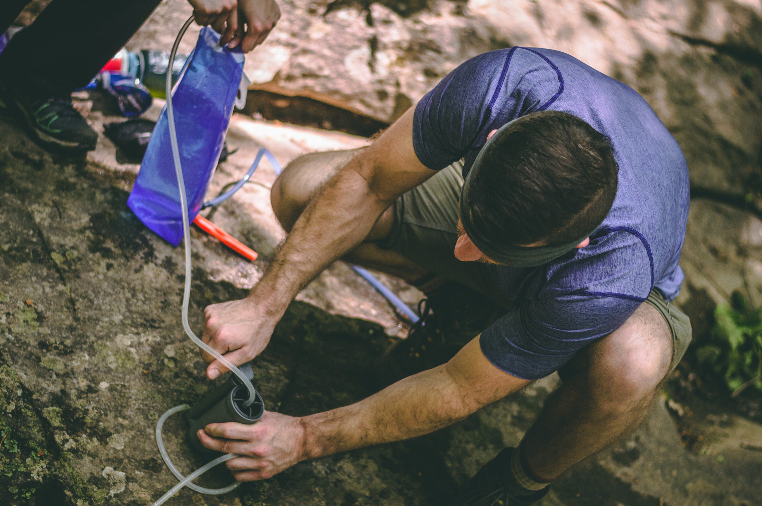 A backpacker filters water at a stream.