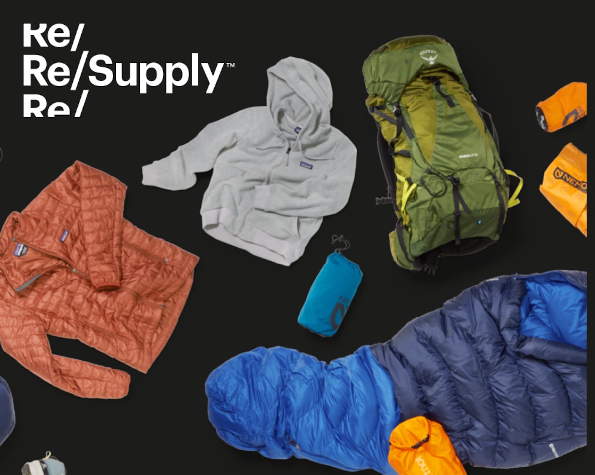 Clothing and camp gear laying flat on a black background.