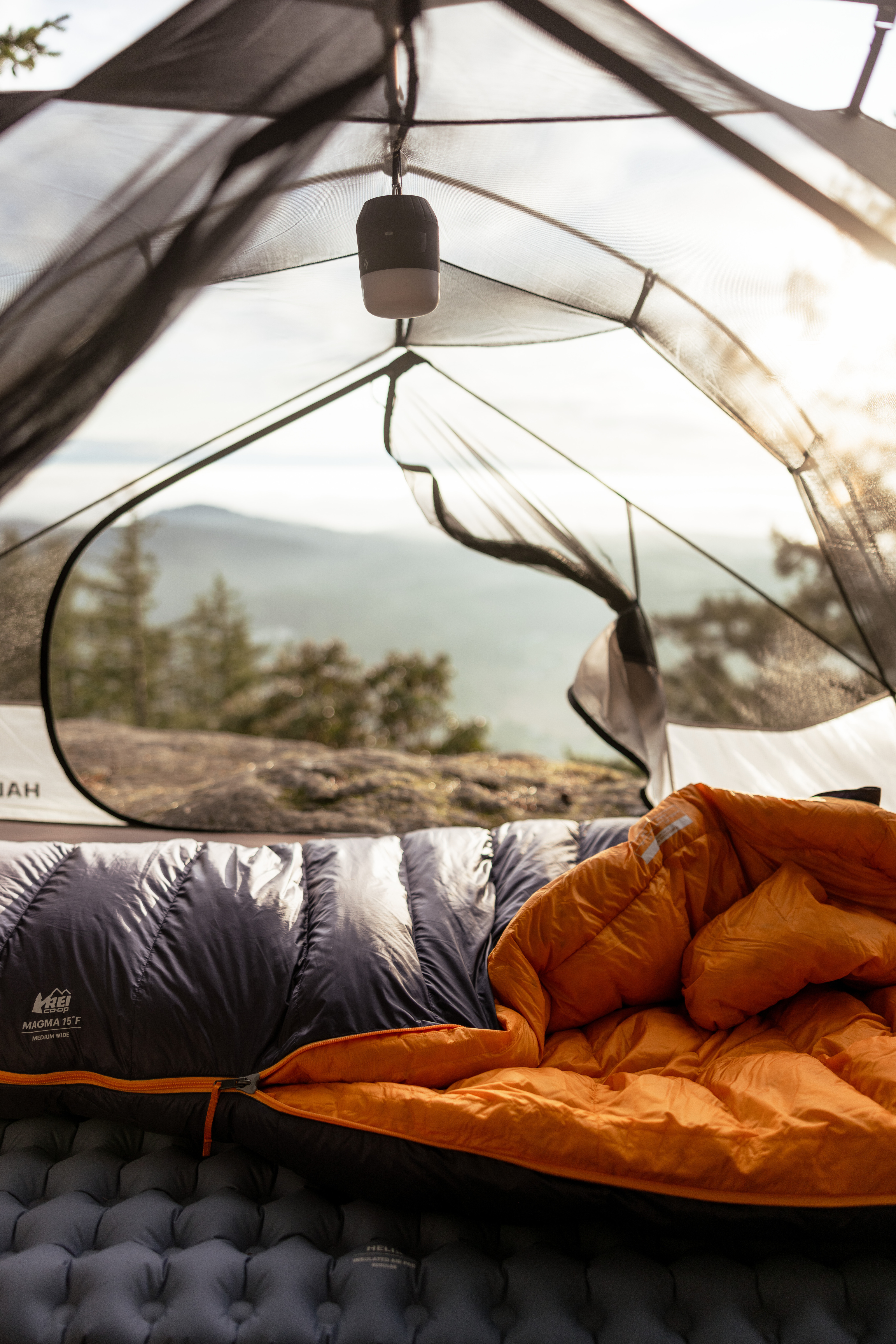 A person relaxes in a sleeping bag inside of a tent.