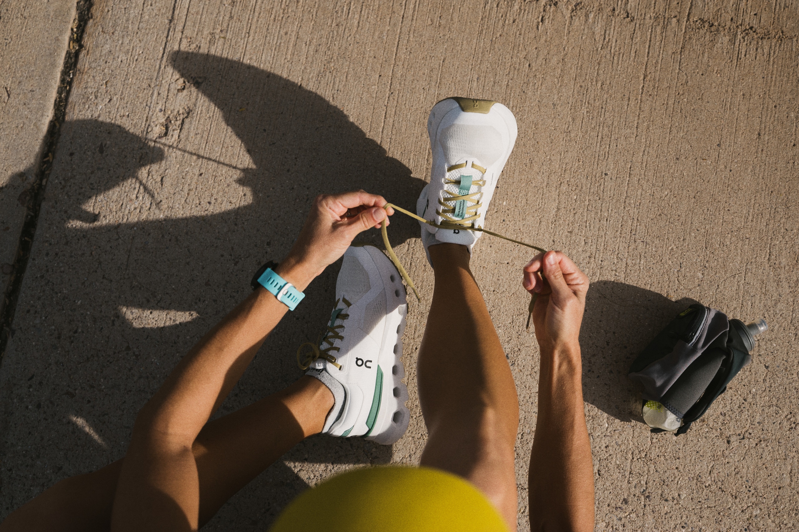 A person sitting down laces up a pair of On Cloud 5 shoes.