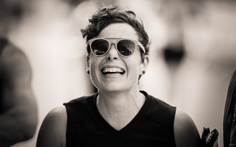 A black and white photo of a person running and smiling wearing goodr sunglasses