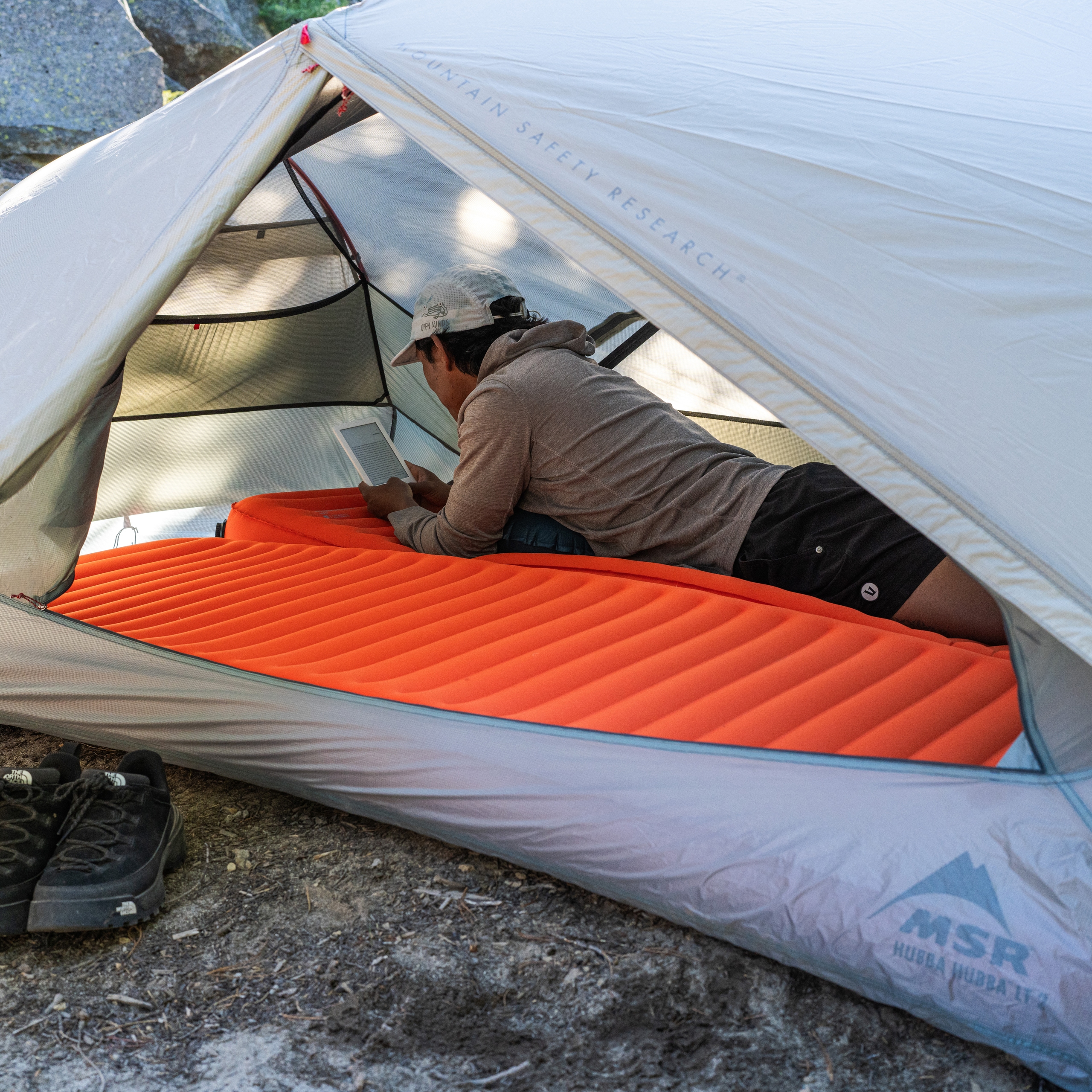 A person lies on the Therm-a-Rest NeoLoft Sleeping Pad inside a grey tent