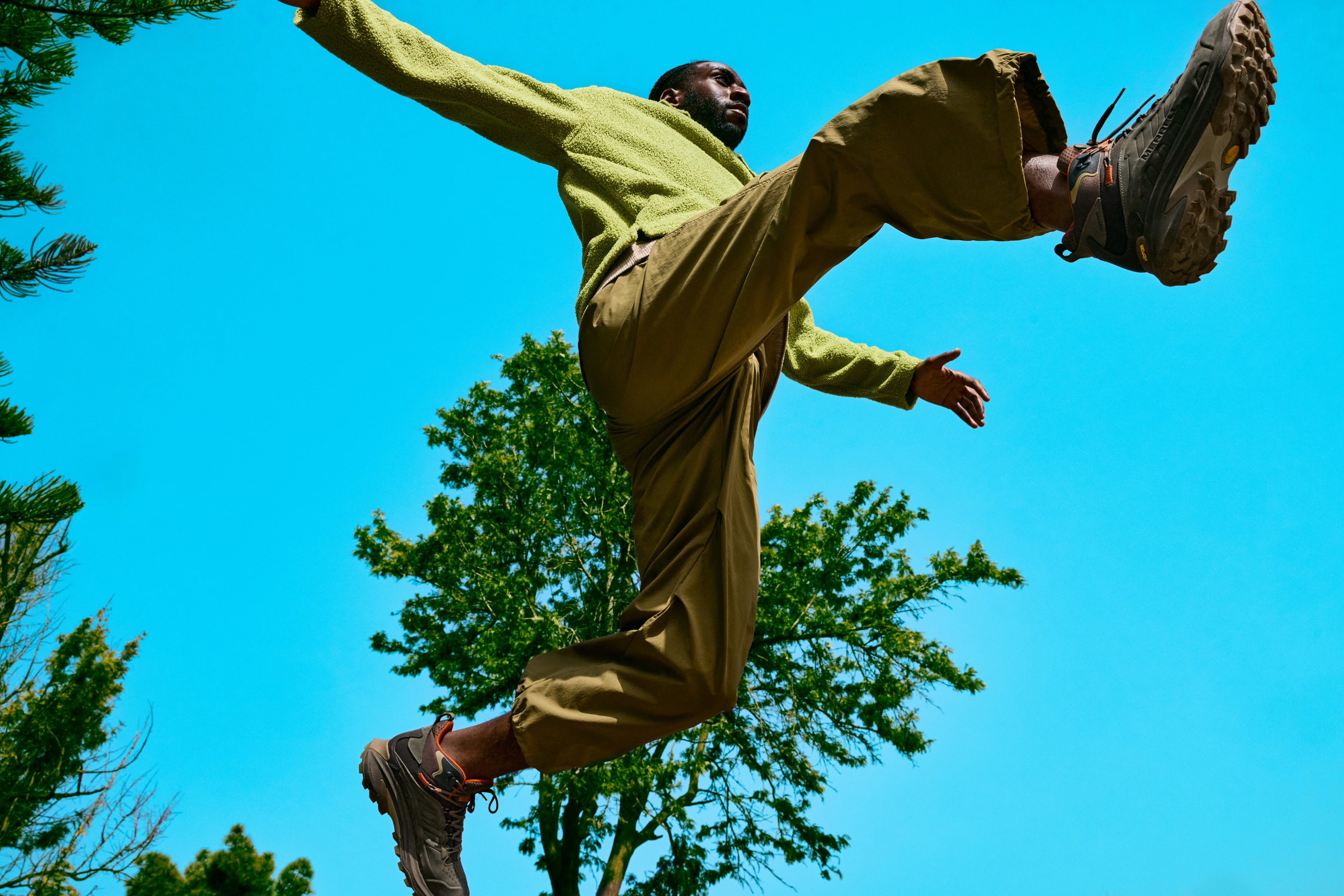 A person leaping over the camera against a bright blue sky