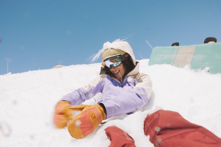 A person buried in snow uses leather mittens to gather snow.