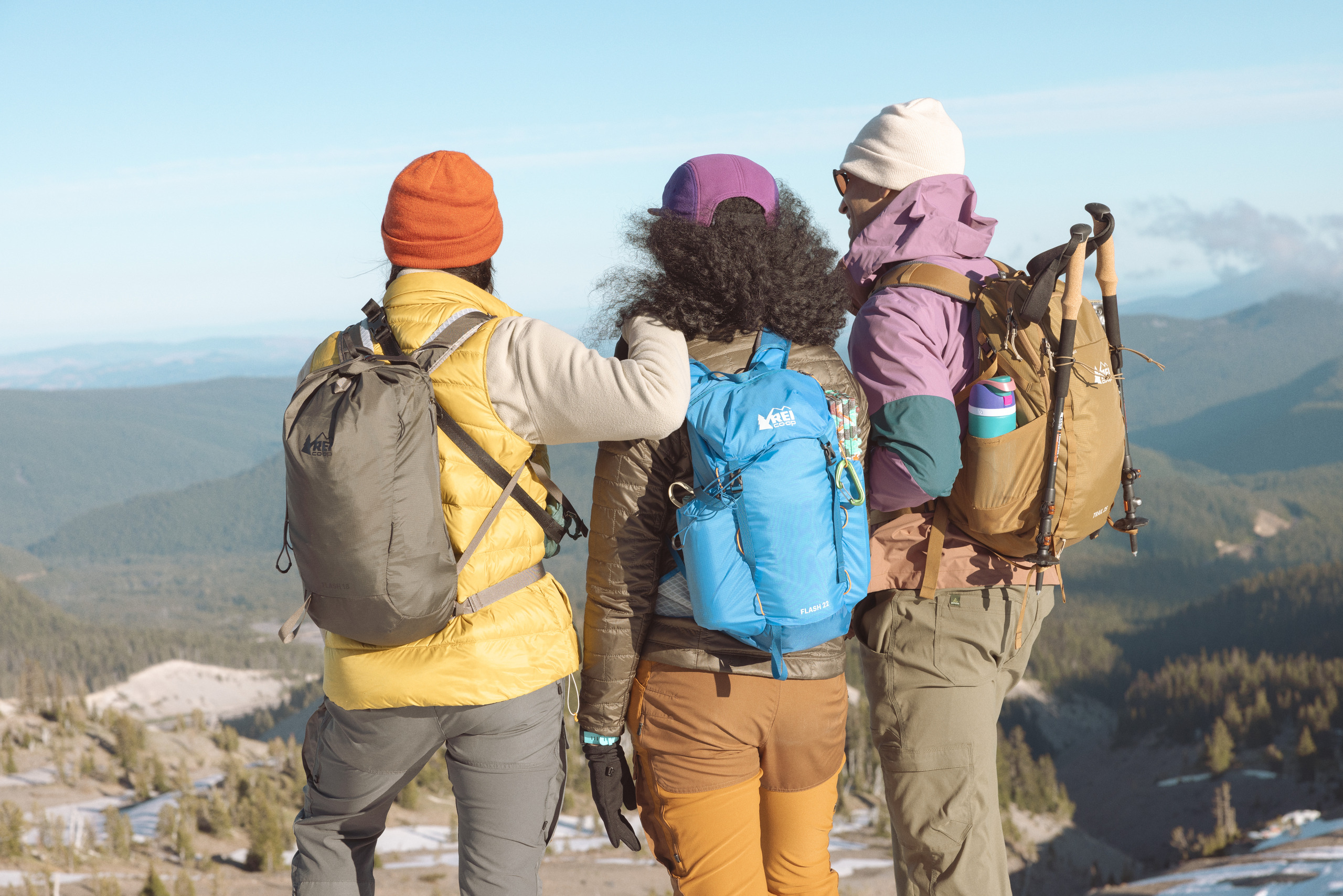 Three people stand at the top of a viewpoint with their backs to the camera