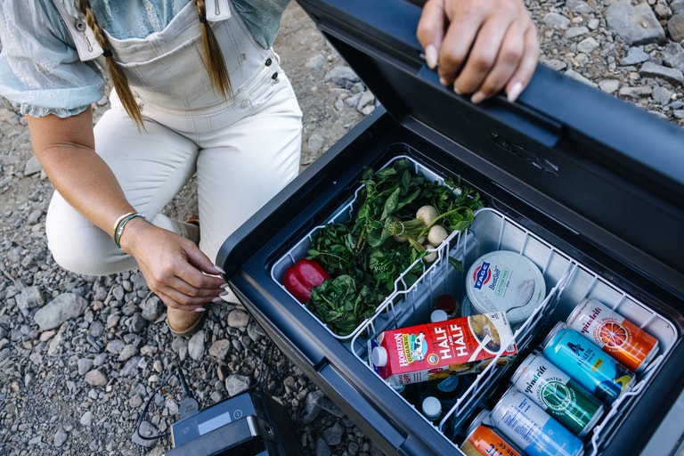 A person opens an electric powered cooler.