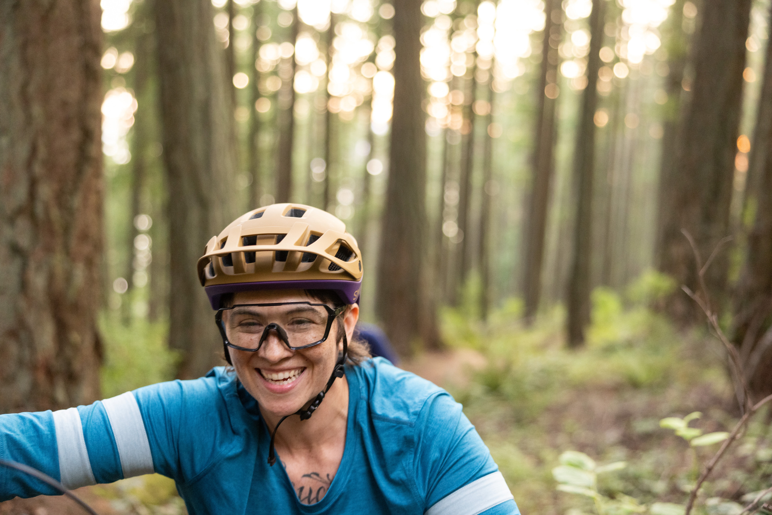 An above-the-chest view of a cyclist wearing a tan helmet, clear-lens goggles, and a blue shirt.
