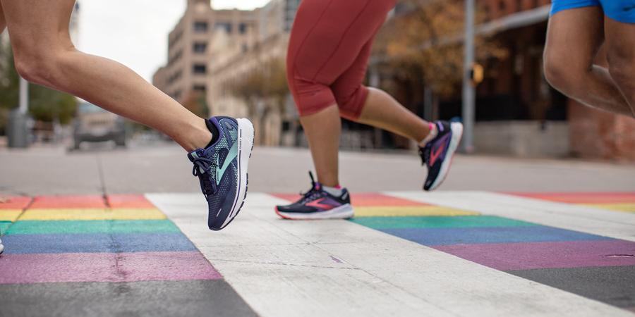 A location image of runners jogging along a paved road with a pride motif painted on it in the Brooks Adrenaline GTS 22s.