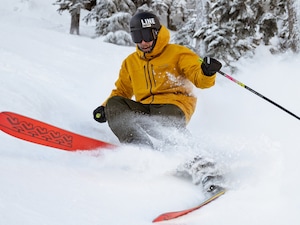 A skier carves through fresh powder on a snowy slope.