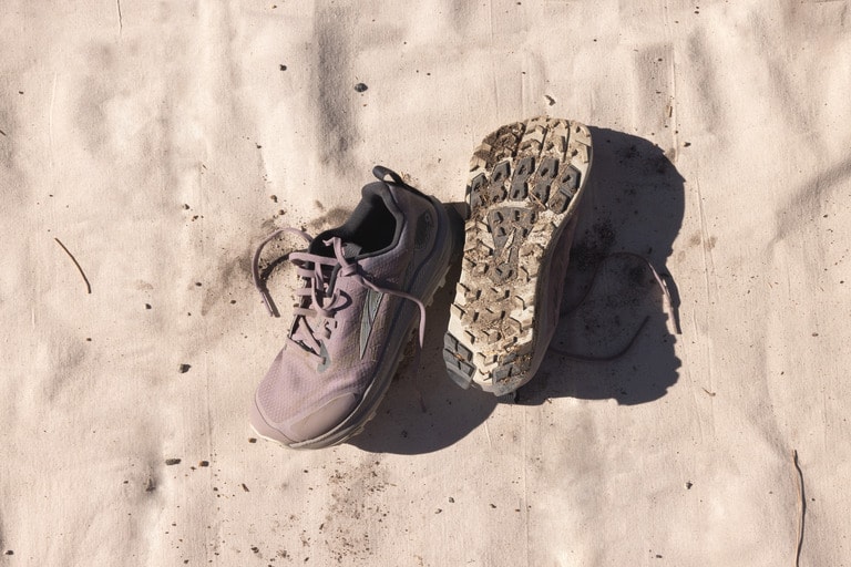 A pair of trail-running shoes shown against dirt