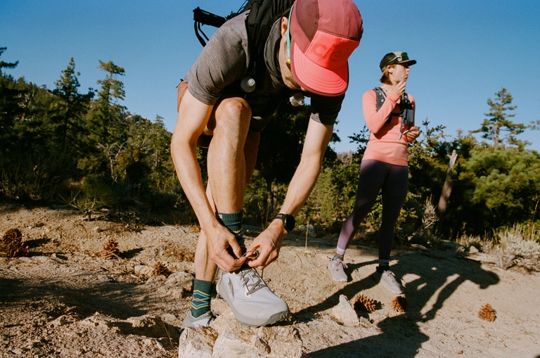 A runner tying his trail-running shoes