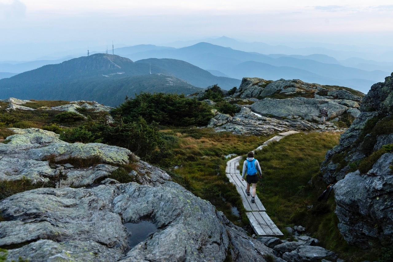A hiker walks on a boardwalk trail through rocky outcroppings