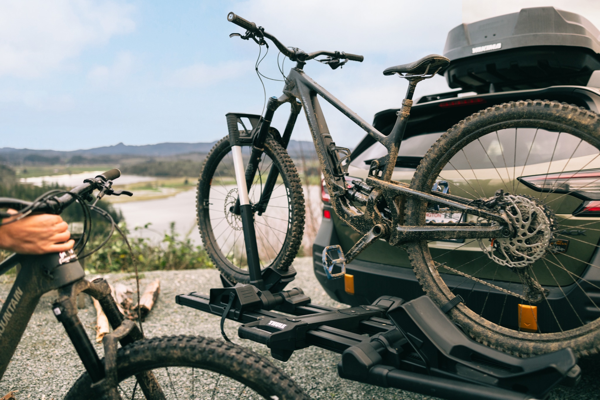 A muddy bike sits on a car rack.
