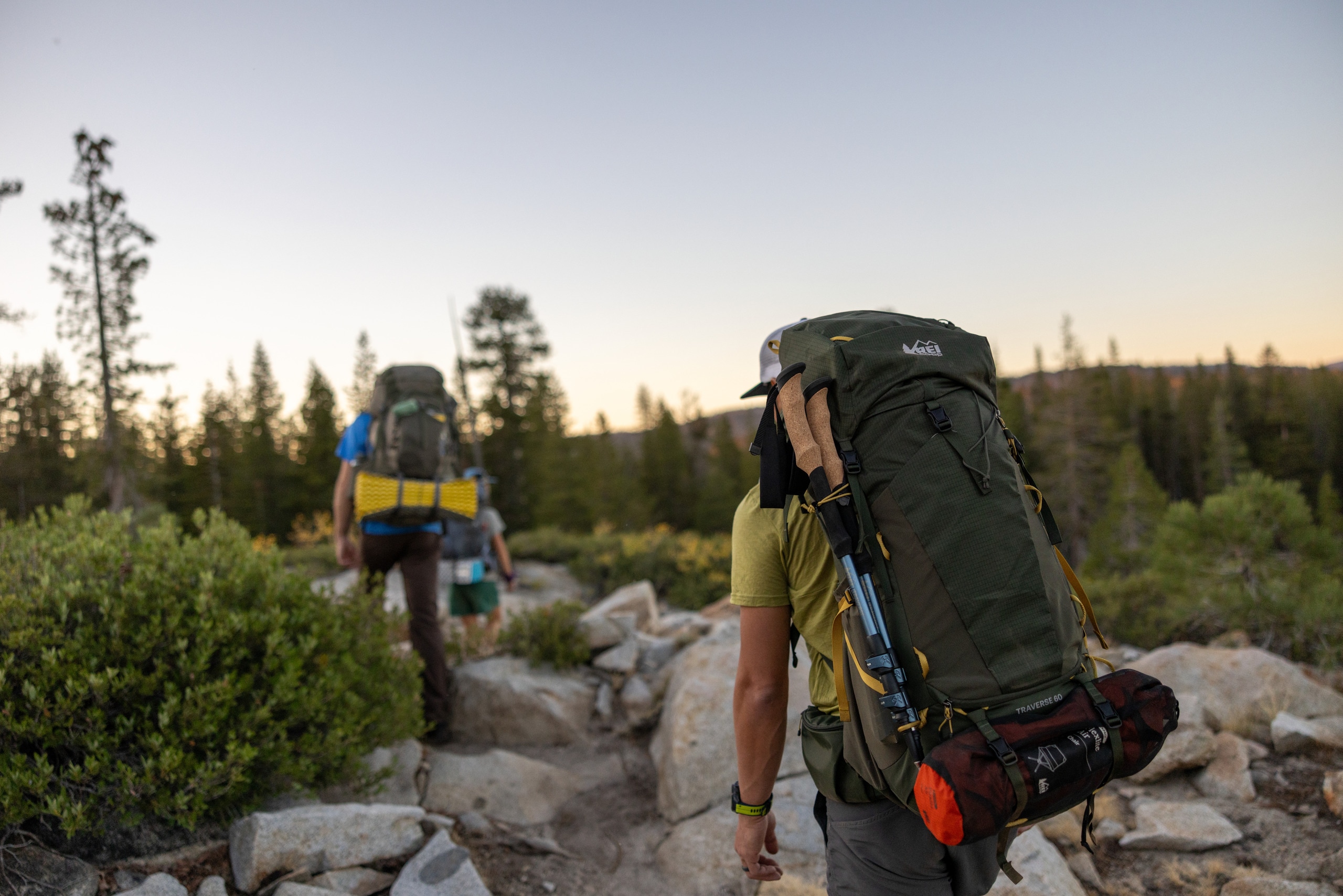 Two people hike over a rocky trail carrying backpacks