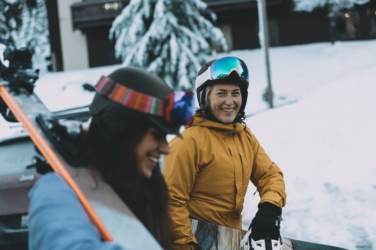 A skier and snowboarder are dressed for a day on the slopes.