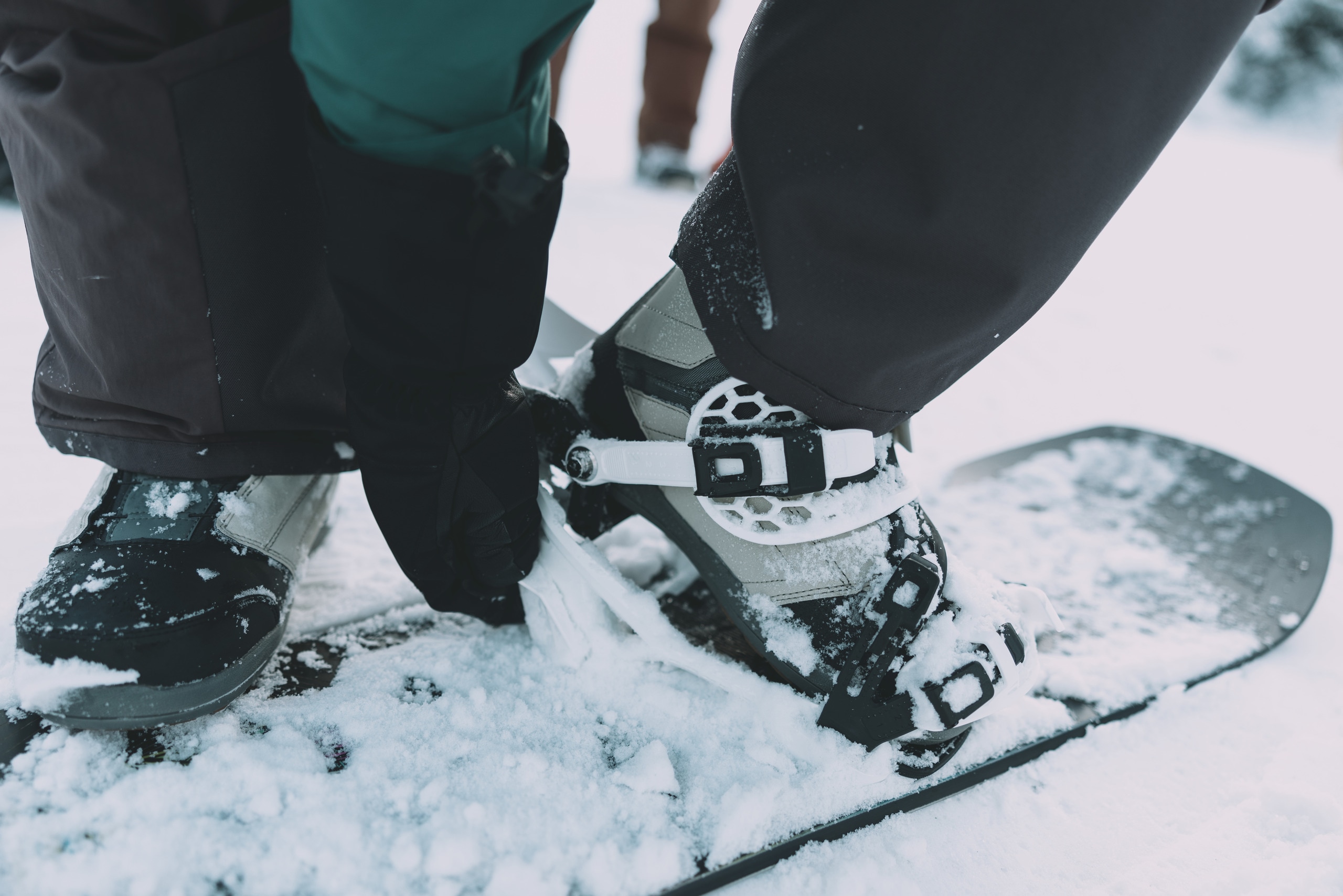 A person gets into their snowboard bindings