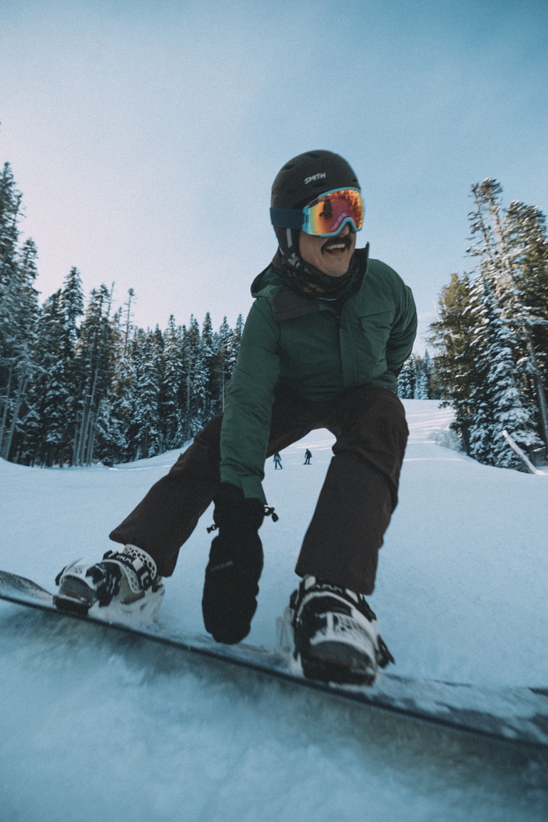 A snowboarder grabs his board as he carves.