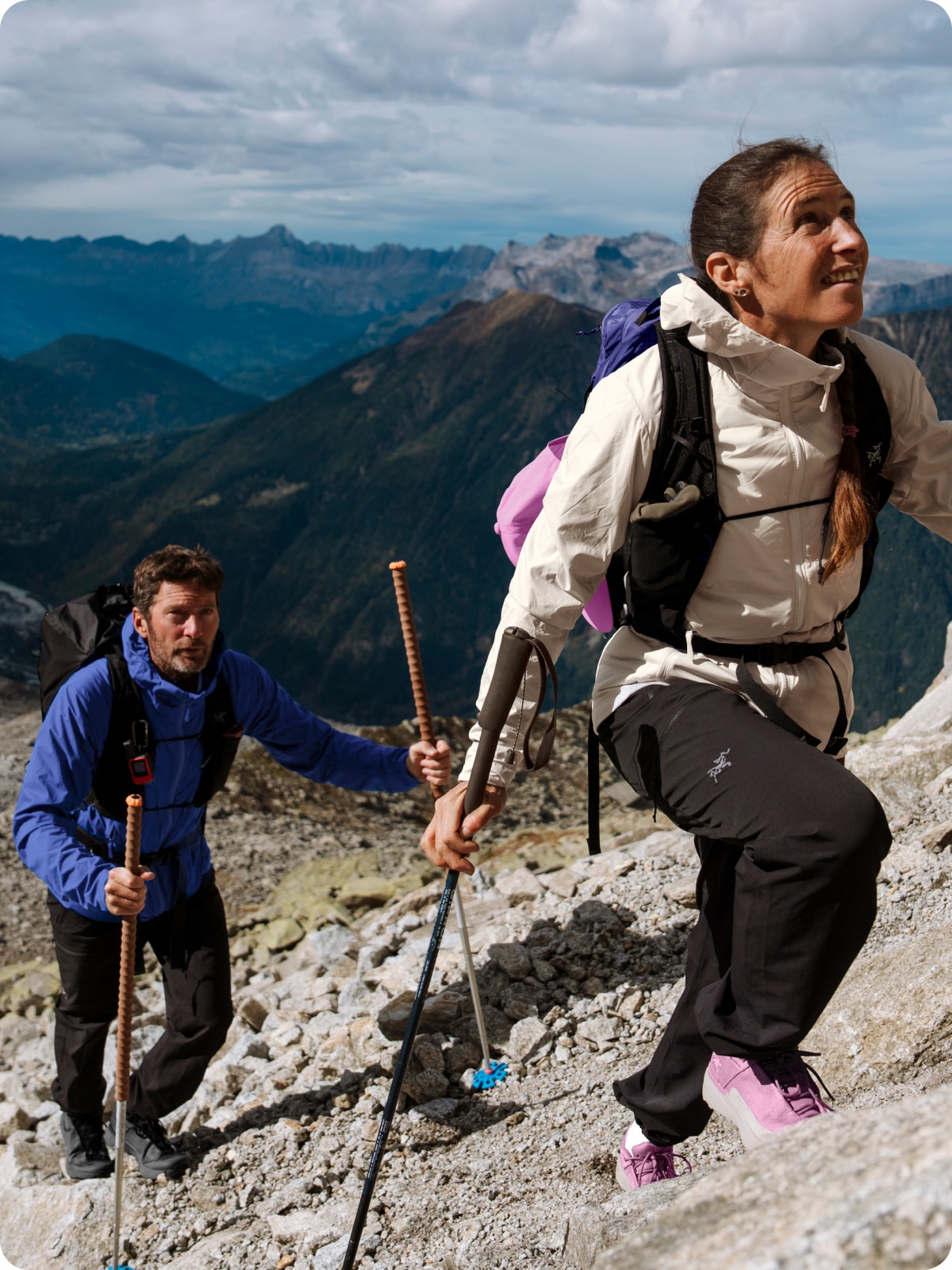 Two people trek up a mountain in Arc’teryx gear.