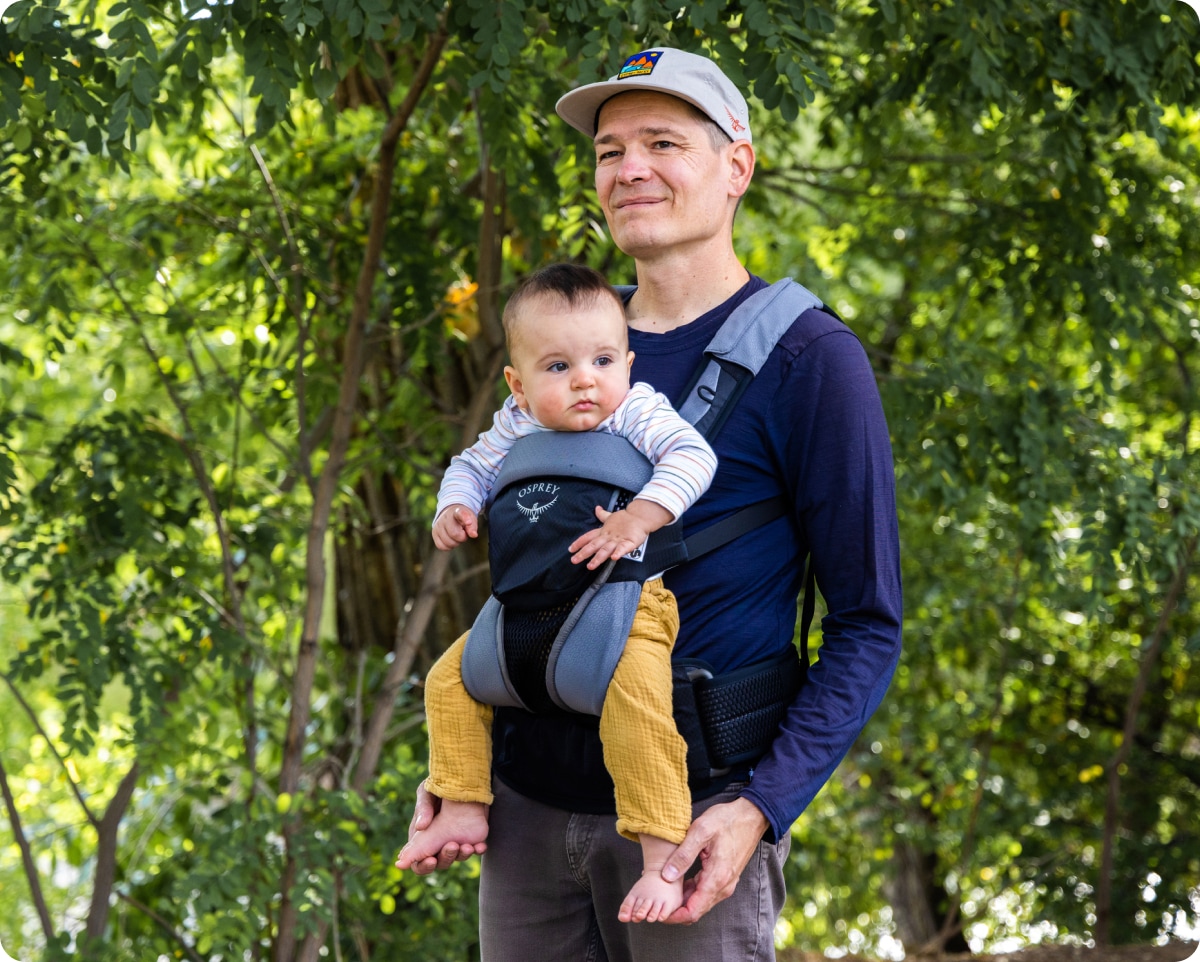 A person enjoys a nature walk with a baby in a carrier.