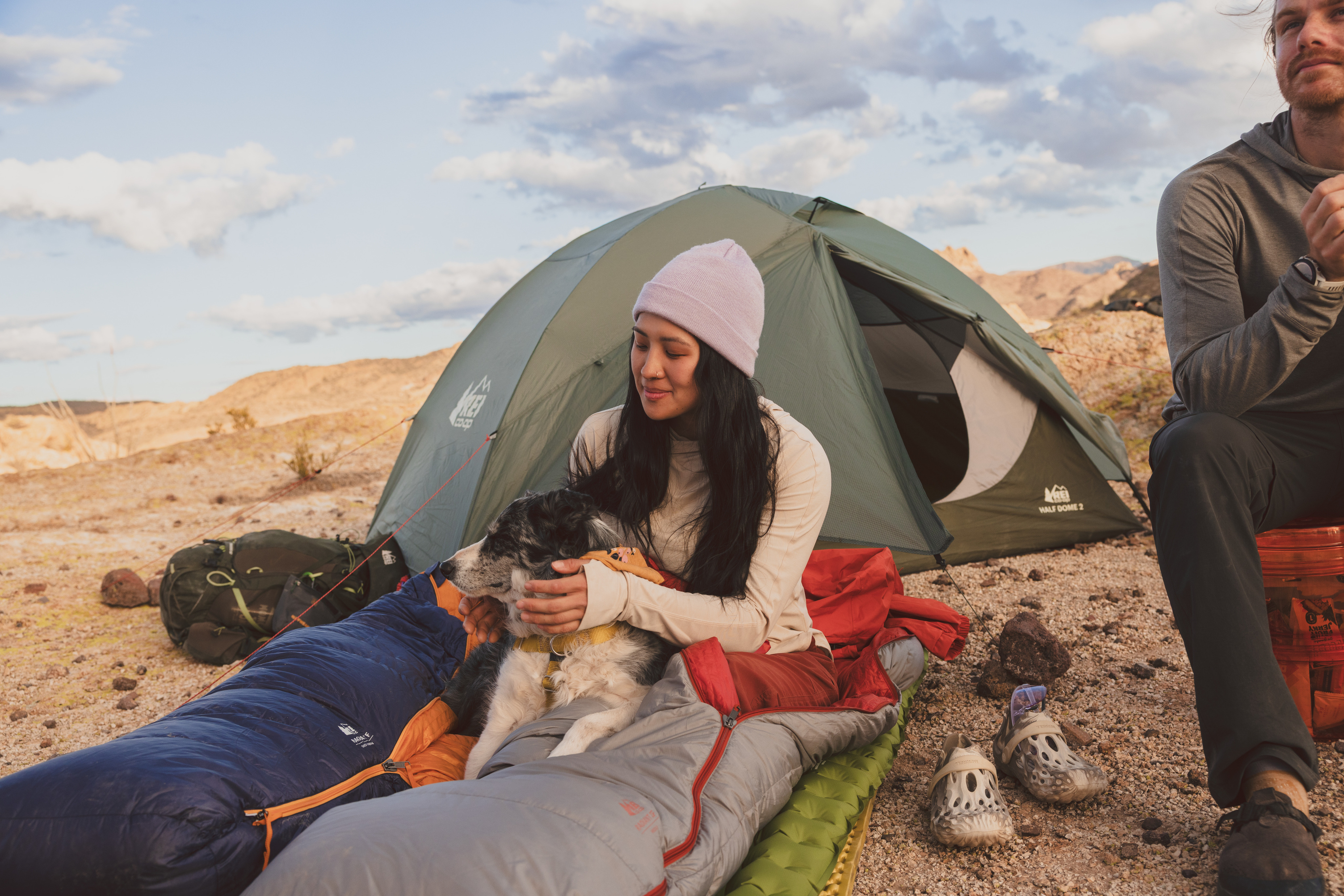 A person relaxes in a sleeping bag with a very good pup.