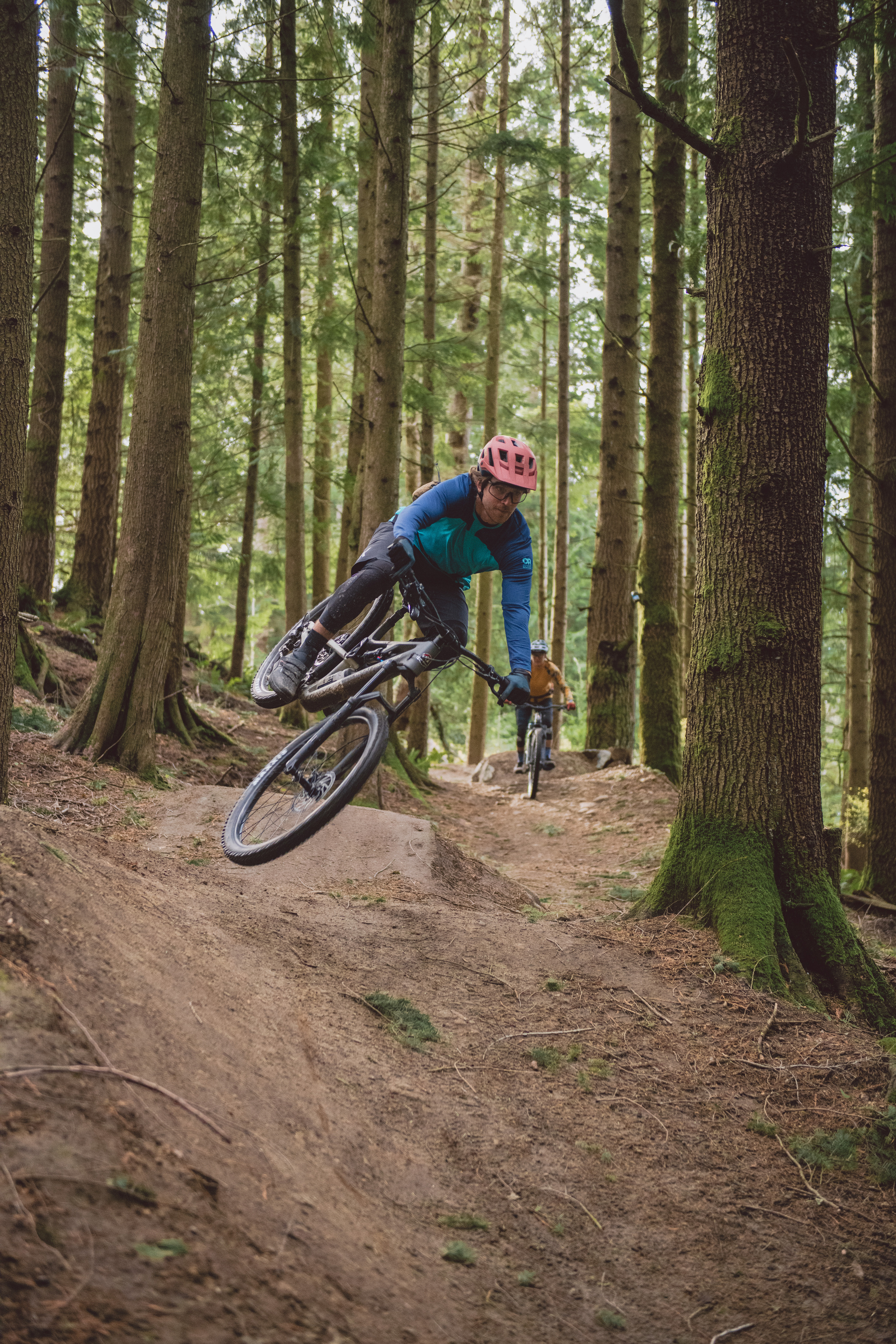 A person riding a mountain bike hits a dirt jump and is shown in air.