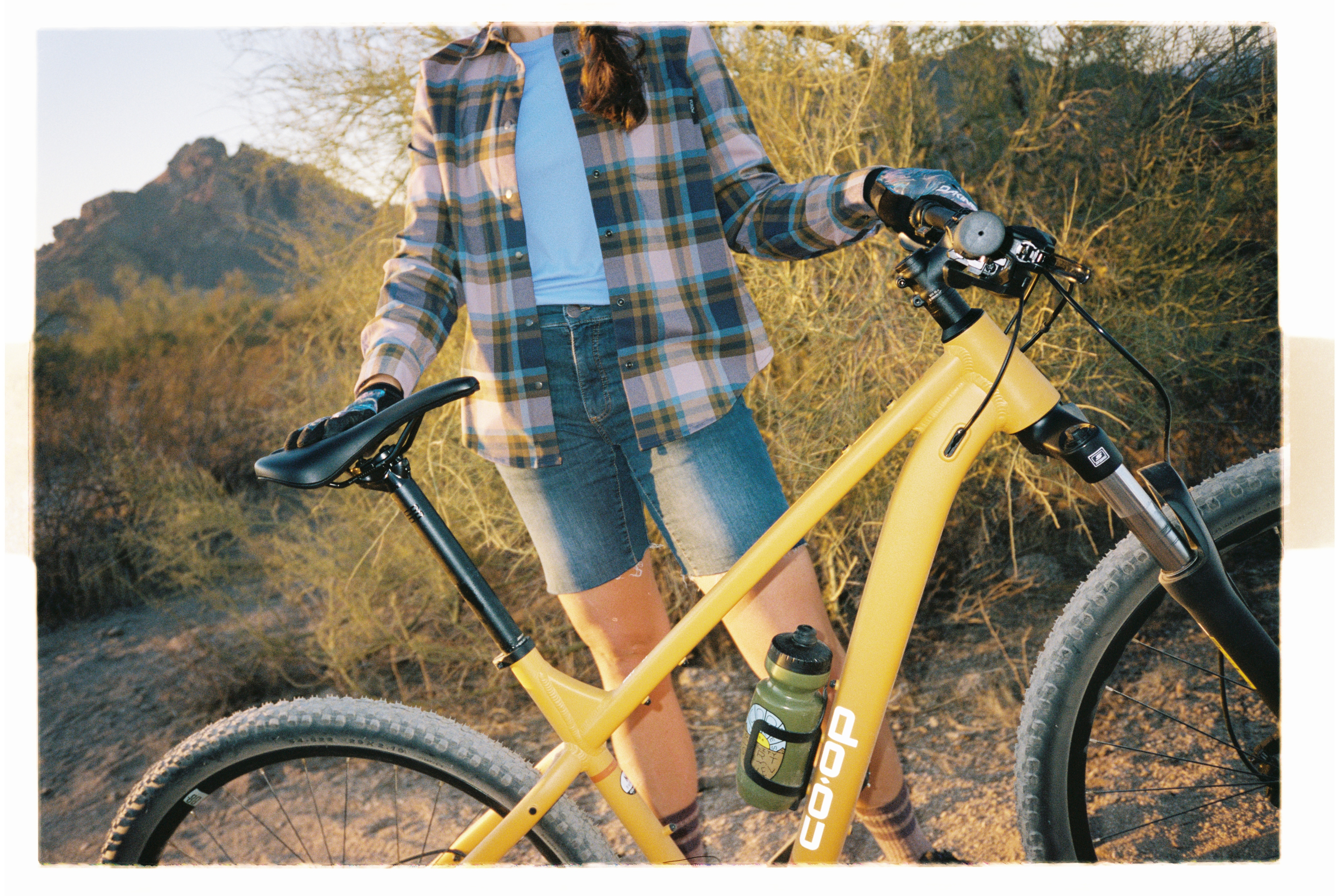 A person poses with their yellow Co-op Cycles bike.