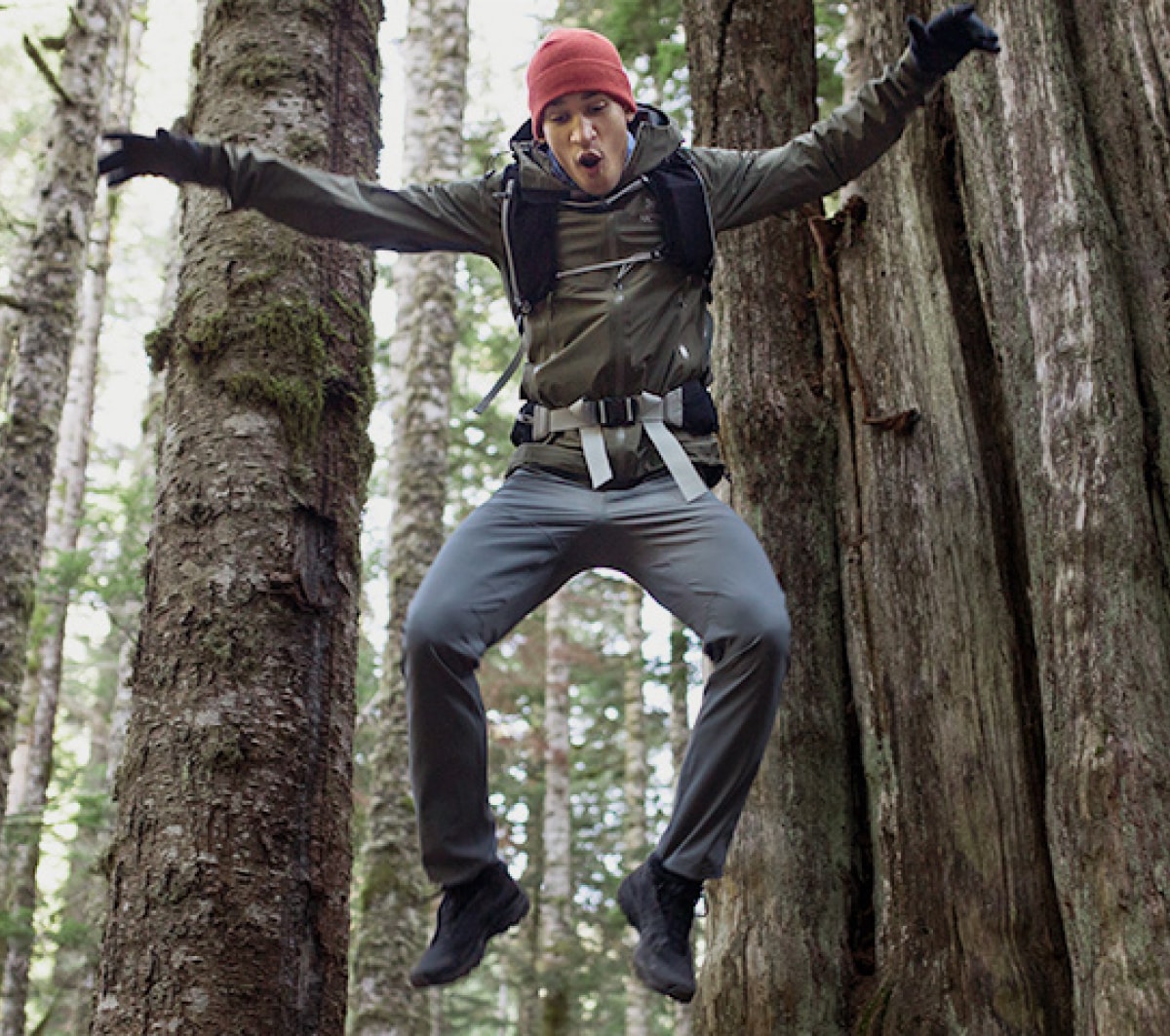 A person jumps playfully in a forest.