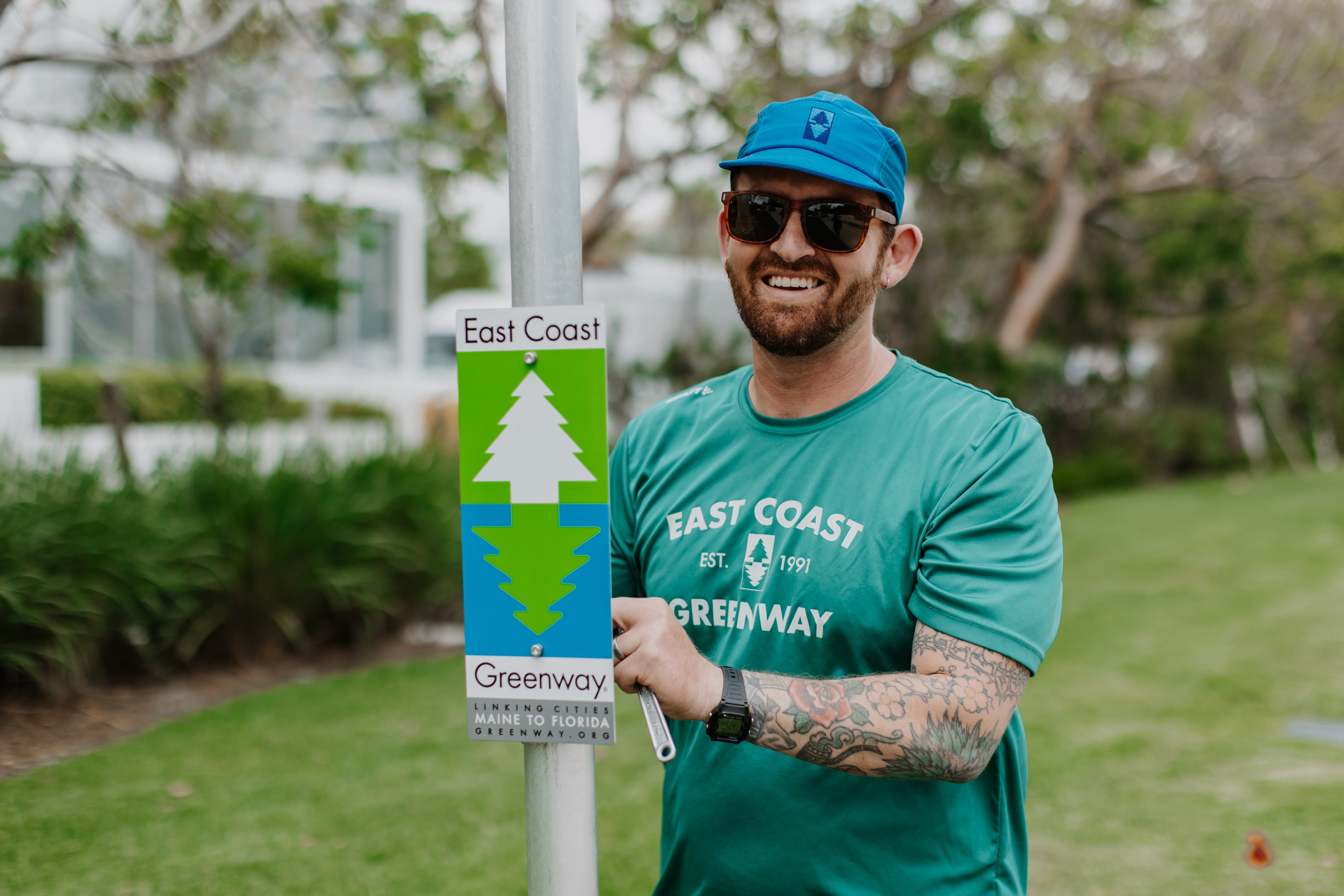 Man standing next to a East Coast Greenway sign