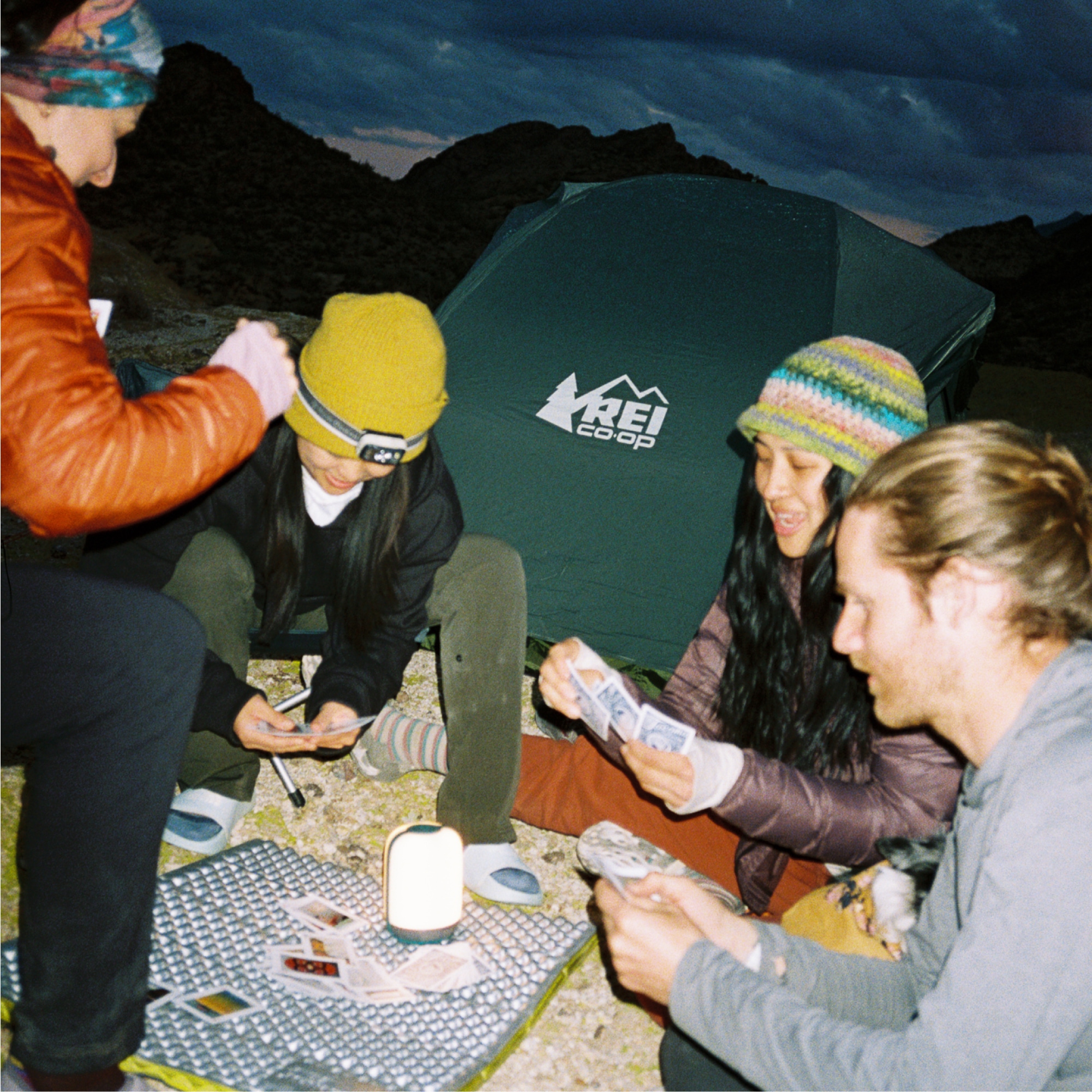 A group of people playing a card game at their campsite.