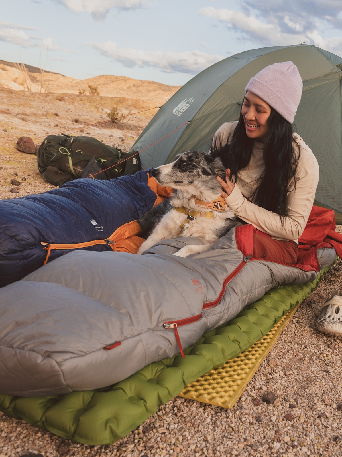 A person and their dog take time to relax in their co-op brand sleeping bag.
