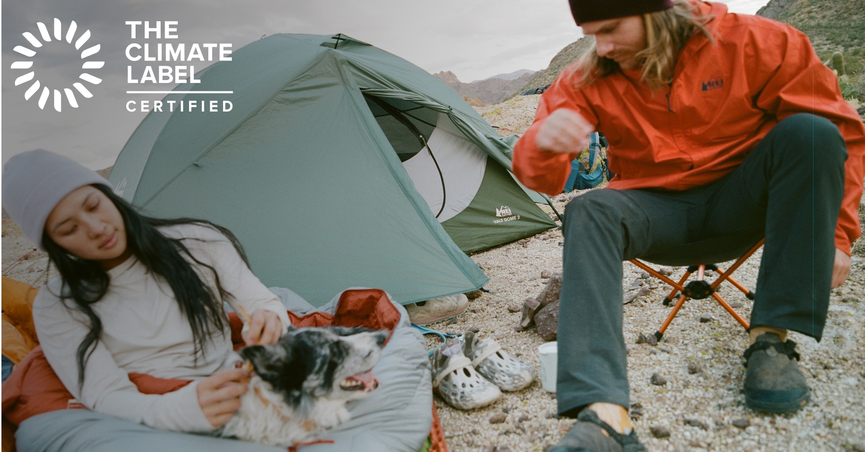 The Climate Label Certified. Two people and their dog relaxing at their campsite.