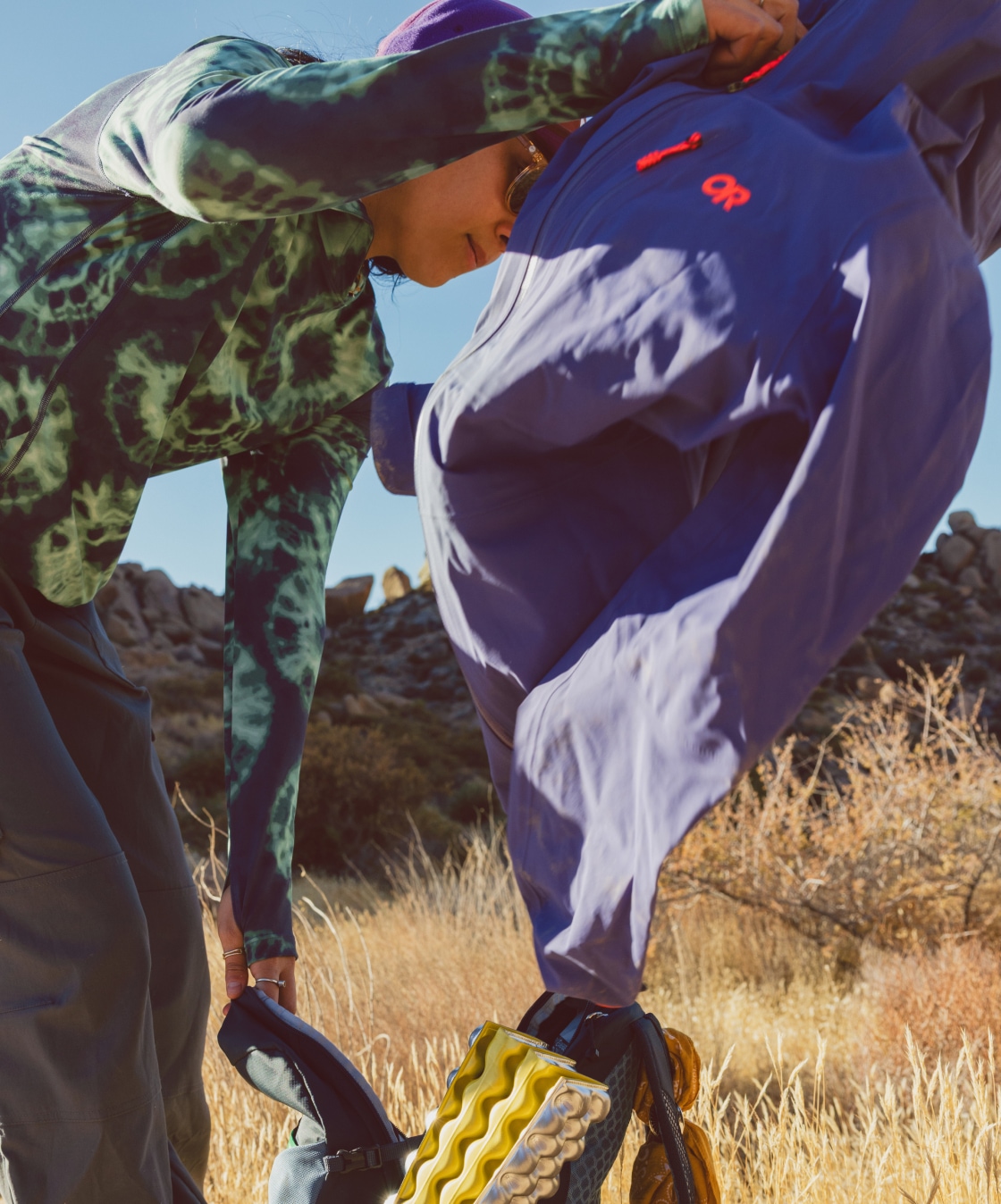 A person pulls their rain jacket out of their hiking pack.