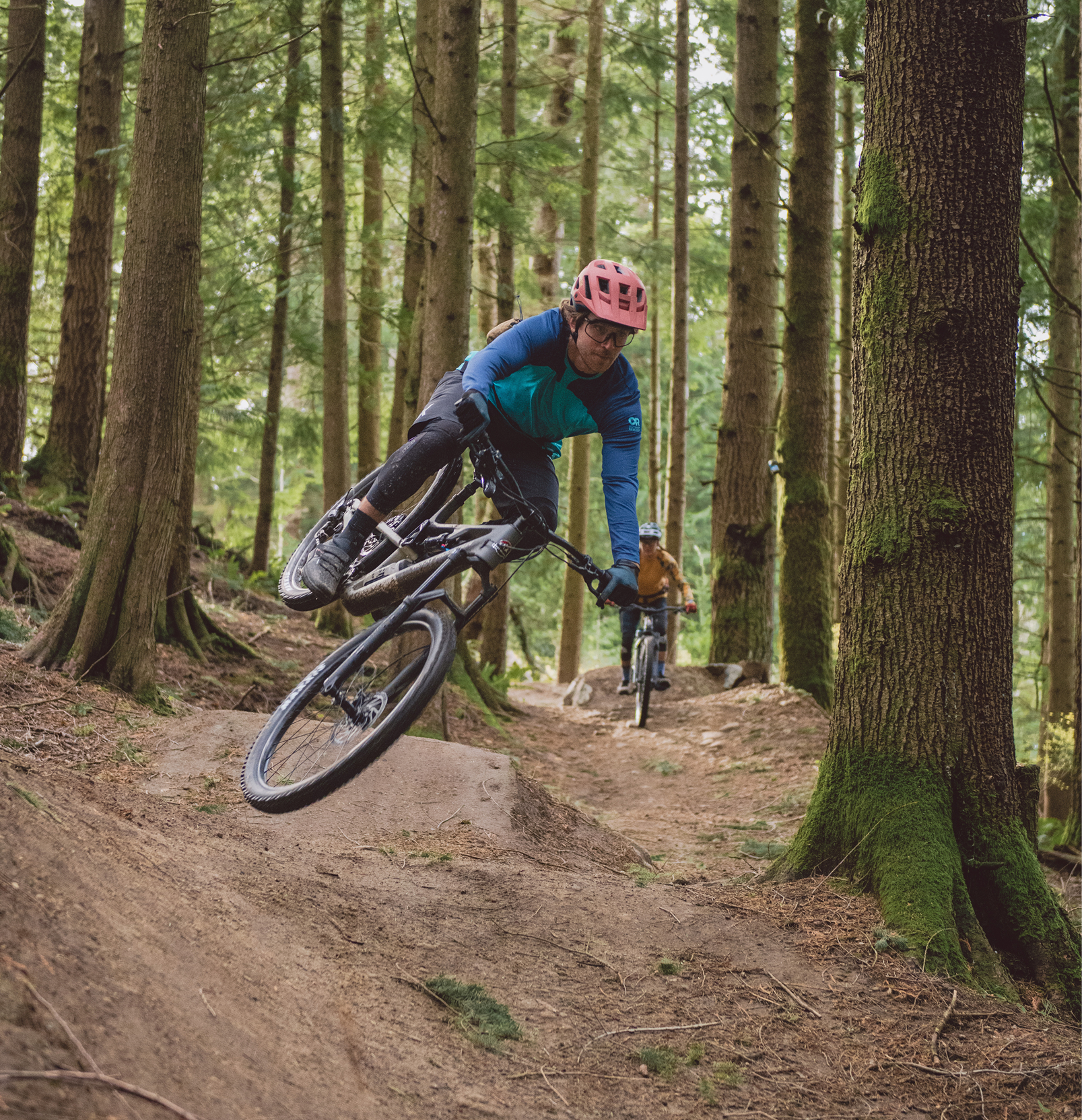 A person rides a mountain bike through a rocky trail in a forest.