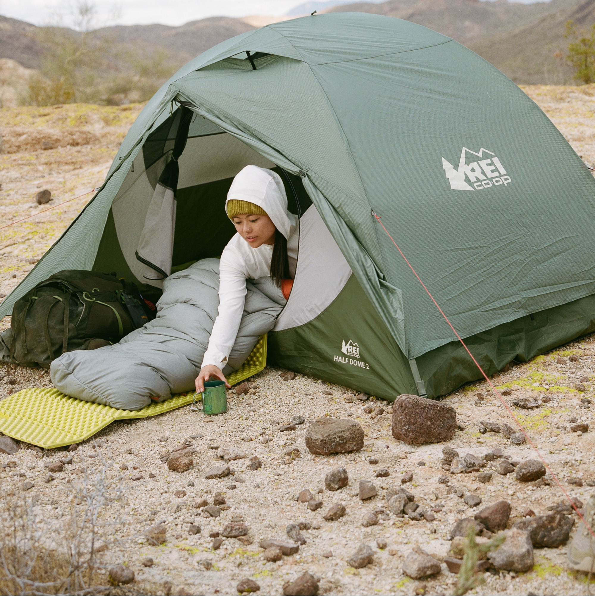 A camper grabs their mug while sitting in their Half Dome tent.