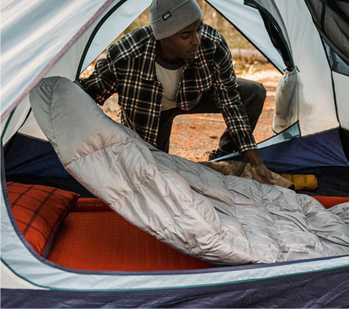 A person sets up their sleeping bag in their tent.