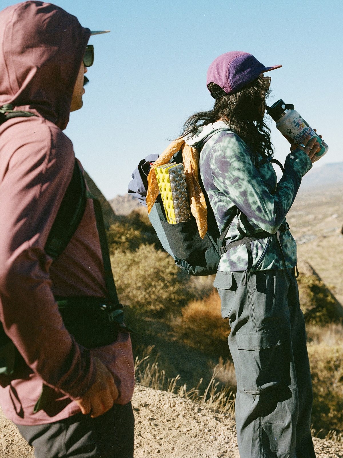 Two people looking off into the distance while they stop to take a break from hiking.