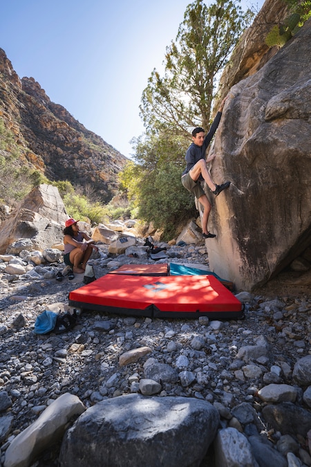 A man is climbing above a crash pad