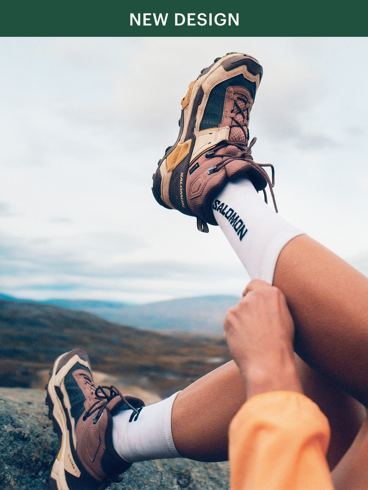 A person pulls up their socks while showing off their Salomon X Ultra 5 shoes.